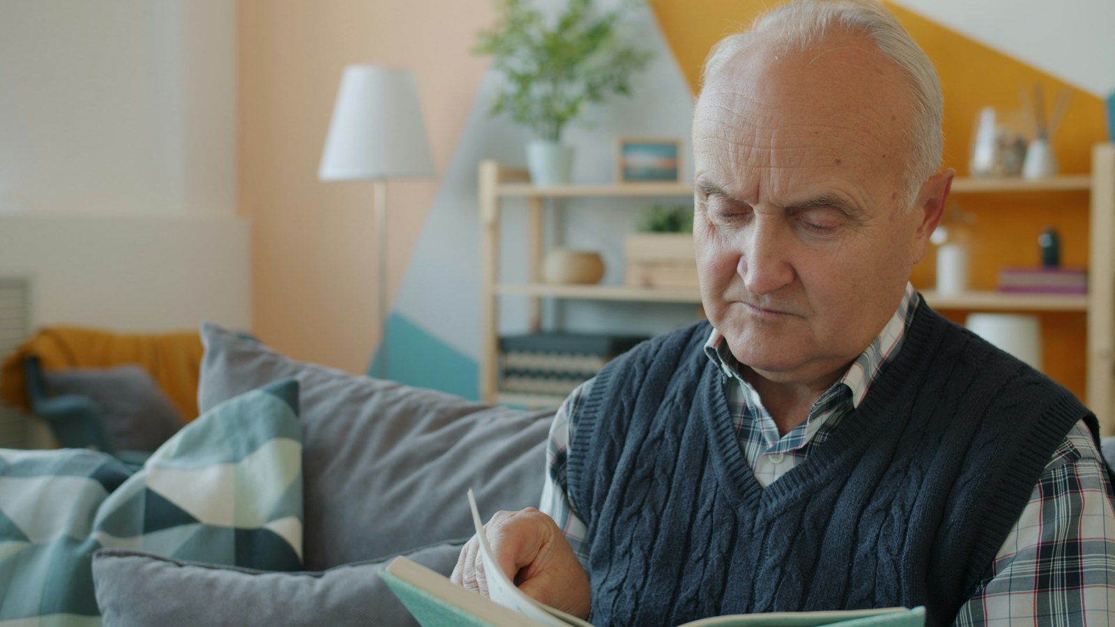 Älterer Mann sitzt Zuhause auf dem Sofa und liest